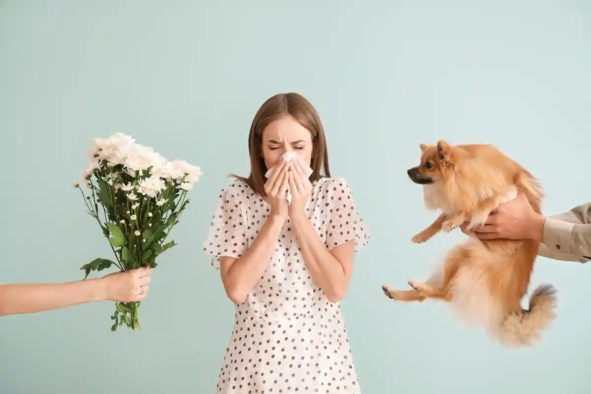 개와 꽃 사이에서 비염으로 힘들어하고 있는 여성