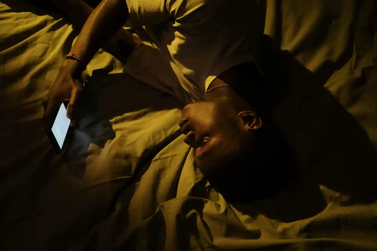 불면증으로 잠이 오지않아 침대에 누워 핸드폰을 보고있는 남성